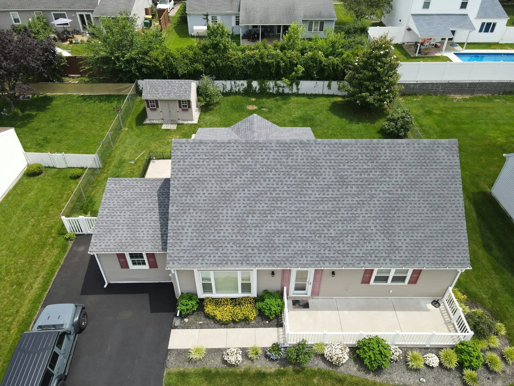 Aerial view of a finished grey shingle roof on a suburban house