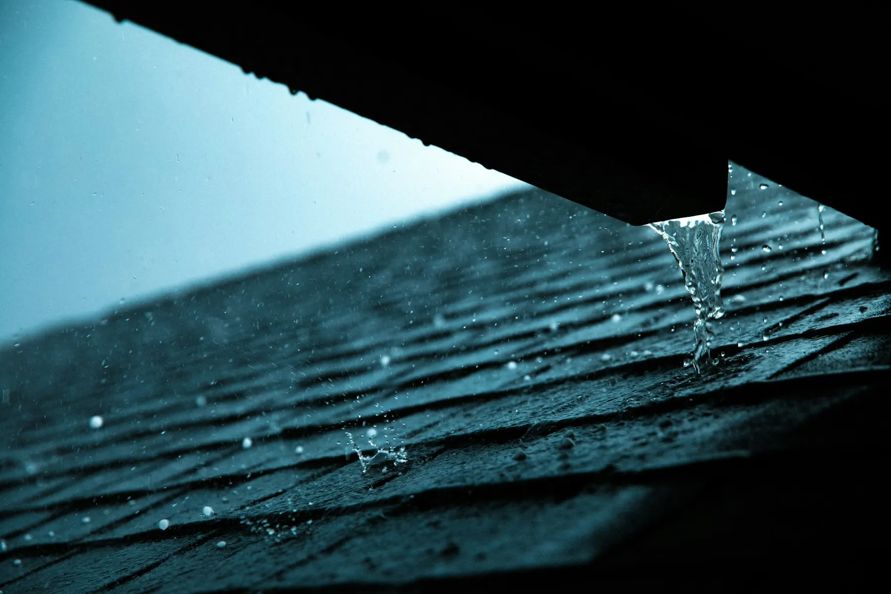 Rain running off the edge of a shingle roof